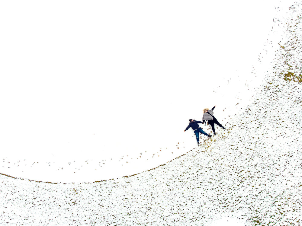 two women hold hands lying in the snow