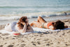two women laying on sandy beach on sunny day