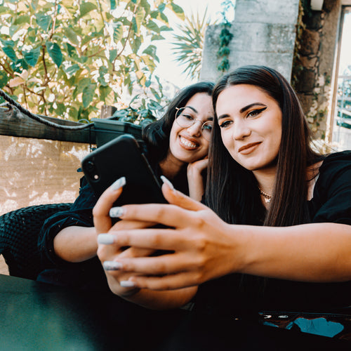 Two Women Lean Into Each Other And Take A Selfie