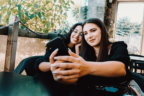 two women lean into each other and take a selfie