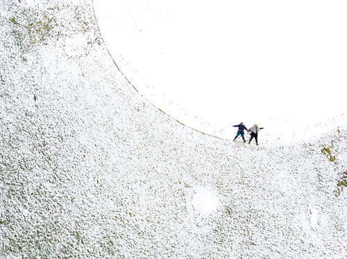 two women make snow angels in a snowy ball field