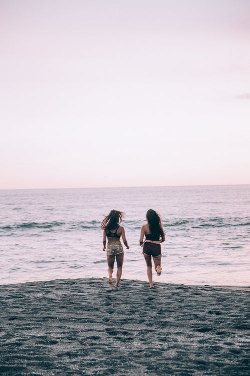 两个女人在夕阳下的海滩上跑步