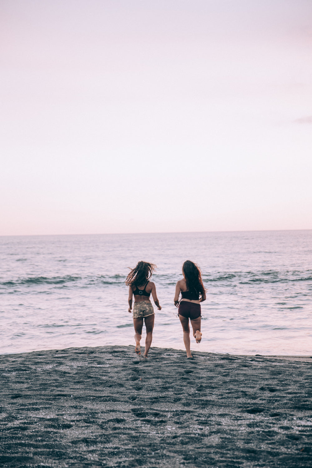 two women run along a sunset beach