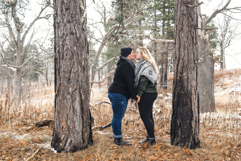 two women sharing a kiss in the woods