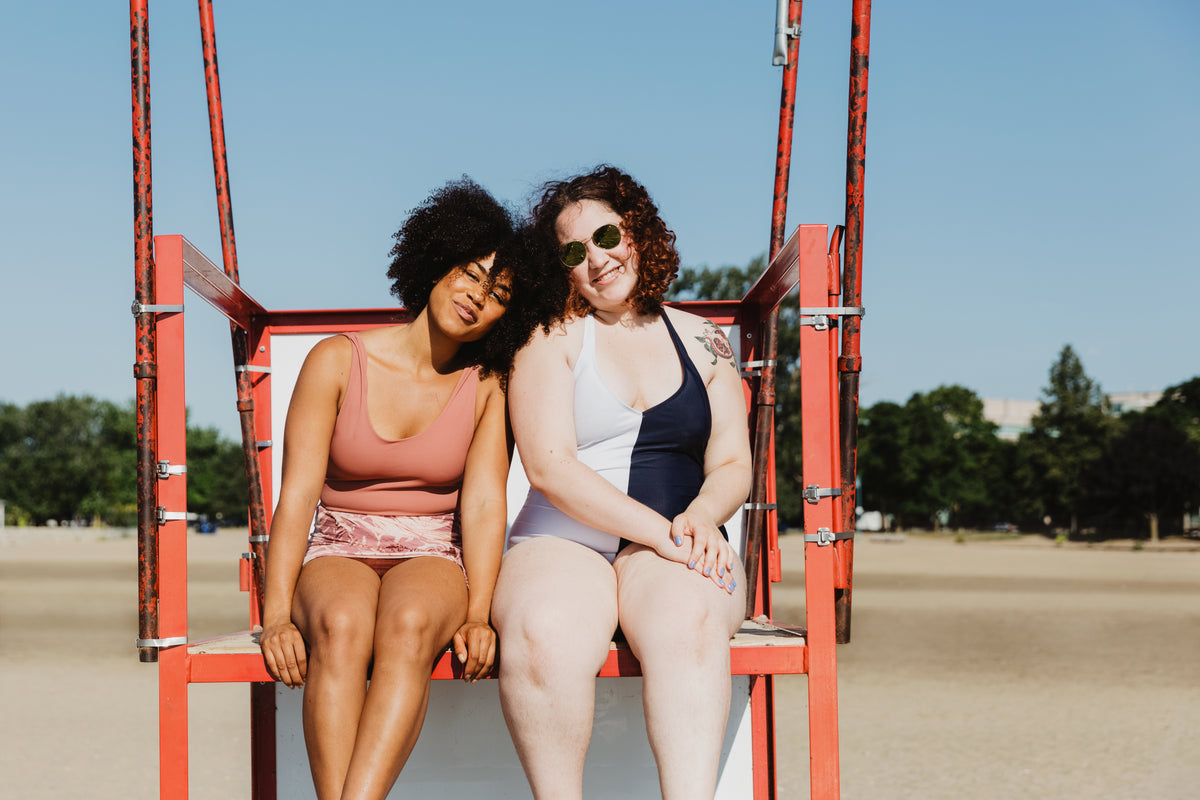 two women sitting on red metal lifeguard chair at beach