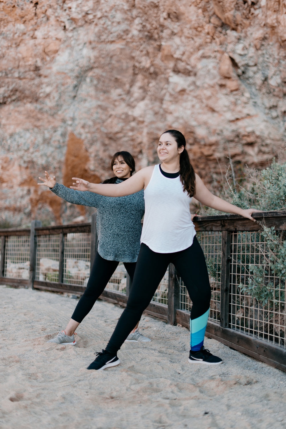 two women strike a yoga pose on the beach