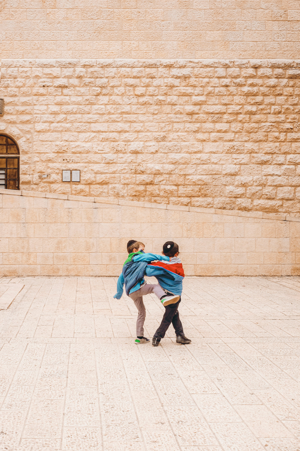 two young people joke around outside of a stone building