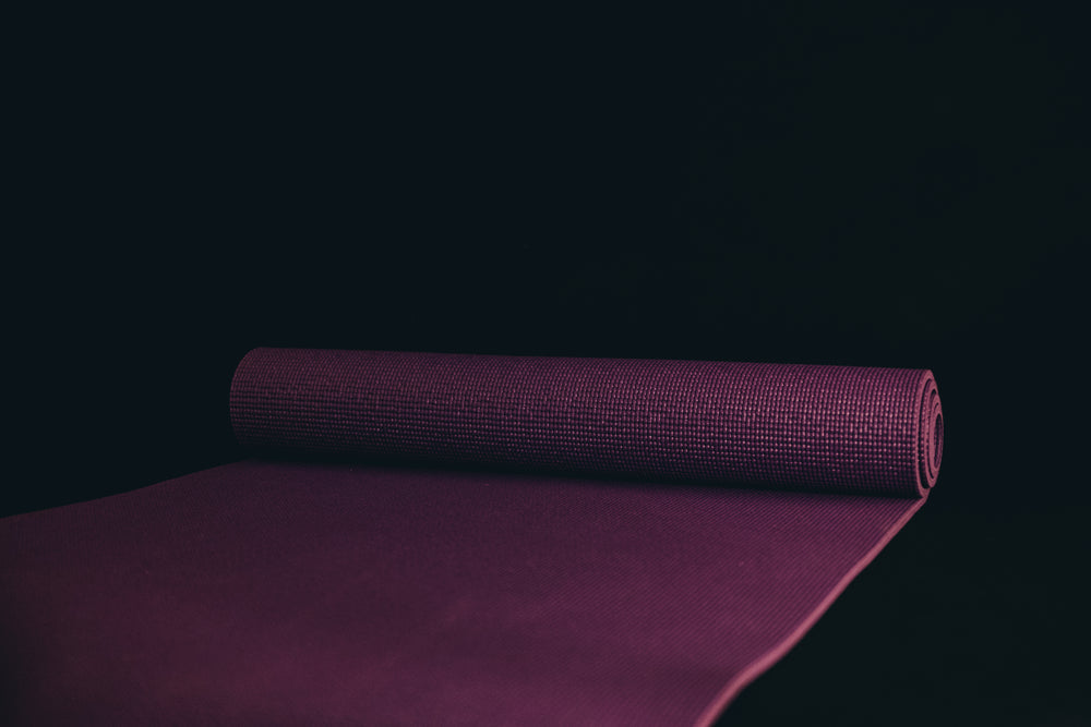 unrolled yoga mat against a black background