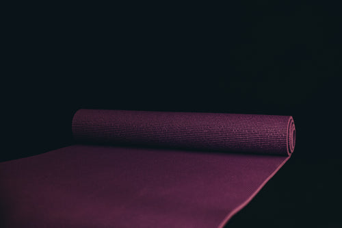 unrolled yoga mat against a black background
