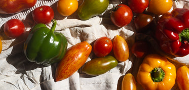 variety of tomatoes and peppers on white cloth