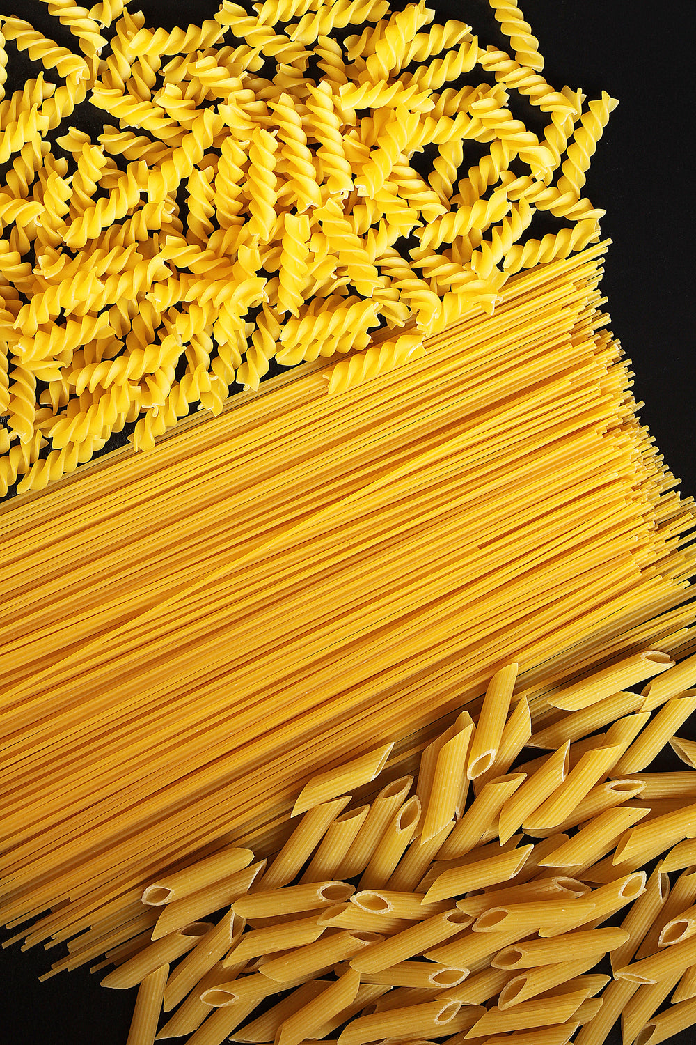 各种类型的uncooked pasta on black counter