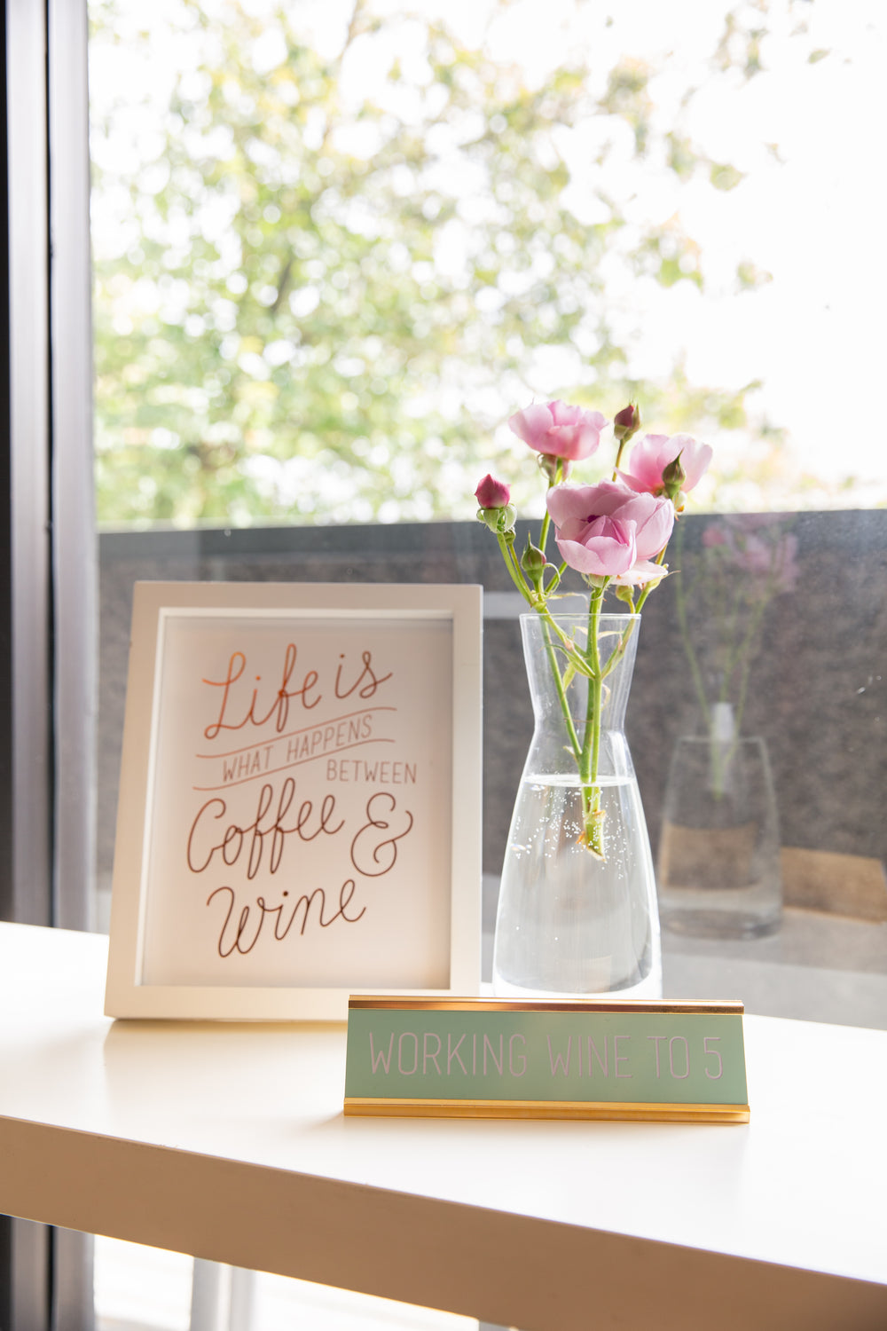 vase with flowers in frame and a sign by a window