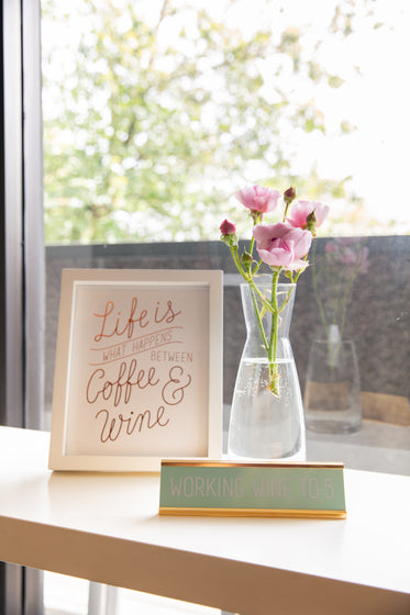 vase with flowers in frame and a sign by a window