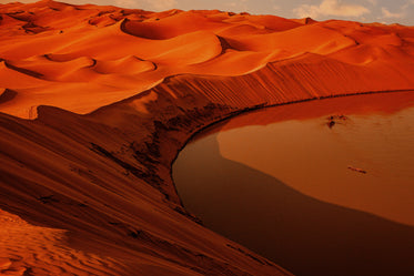 Vibrant Sandy Hills Curve To Meet Still Orange Water