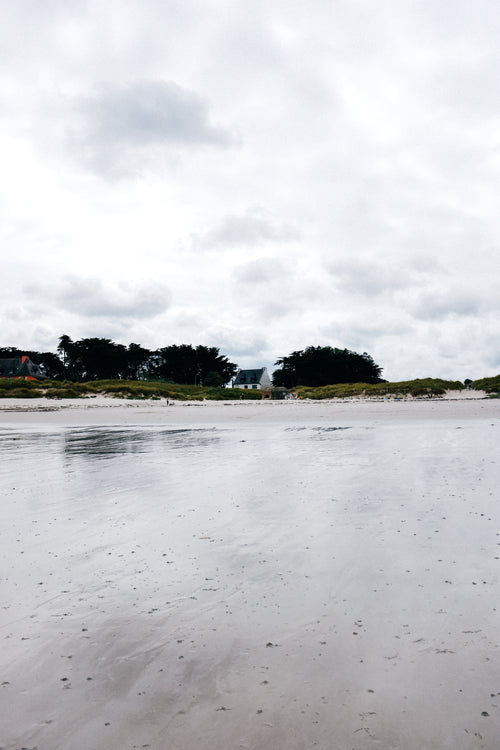 view of a distant house from a wet sandy beach