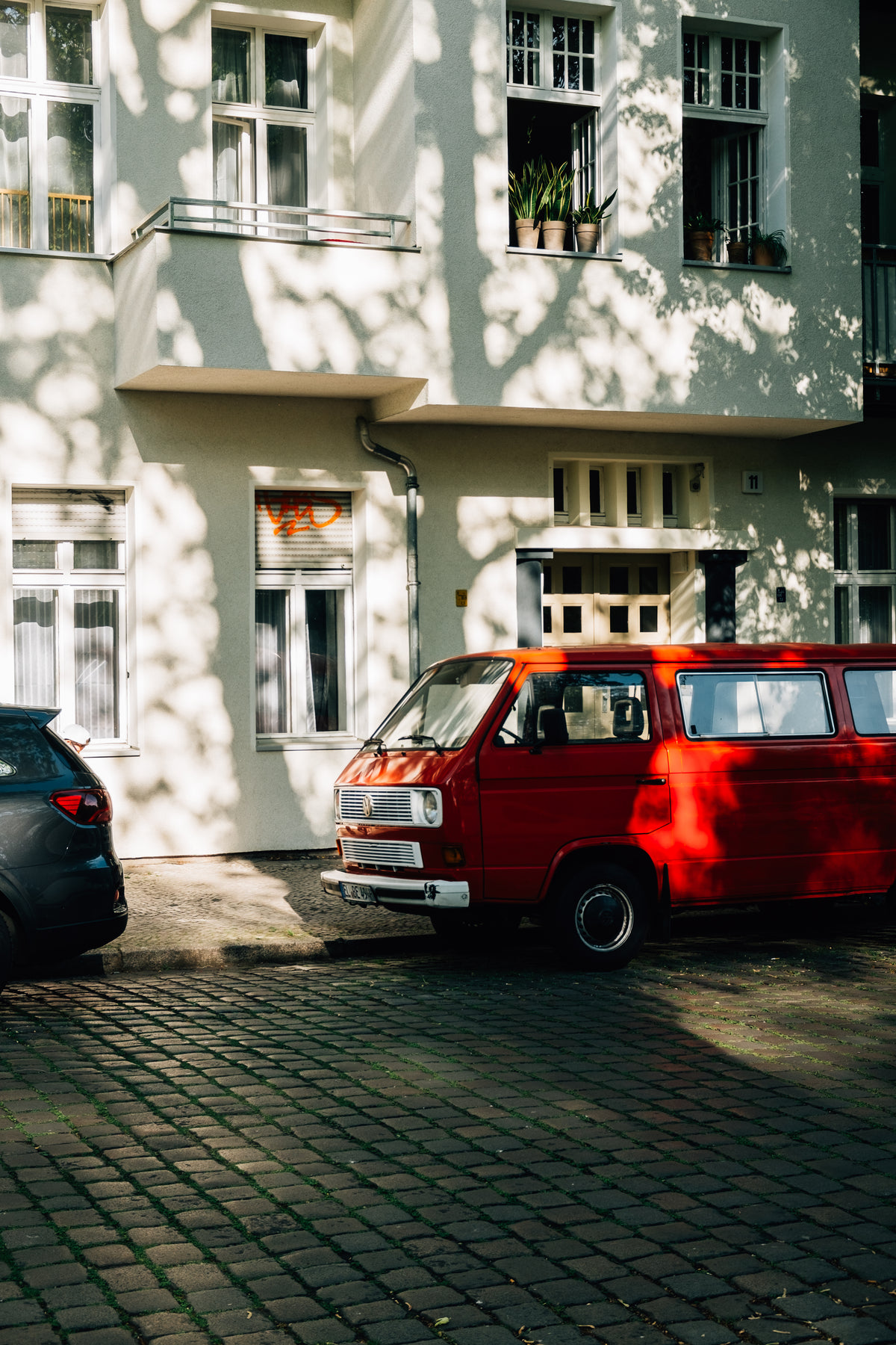 老式红色面包车停在一栋白色建筑旁