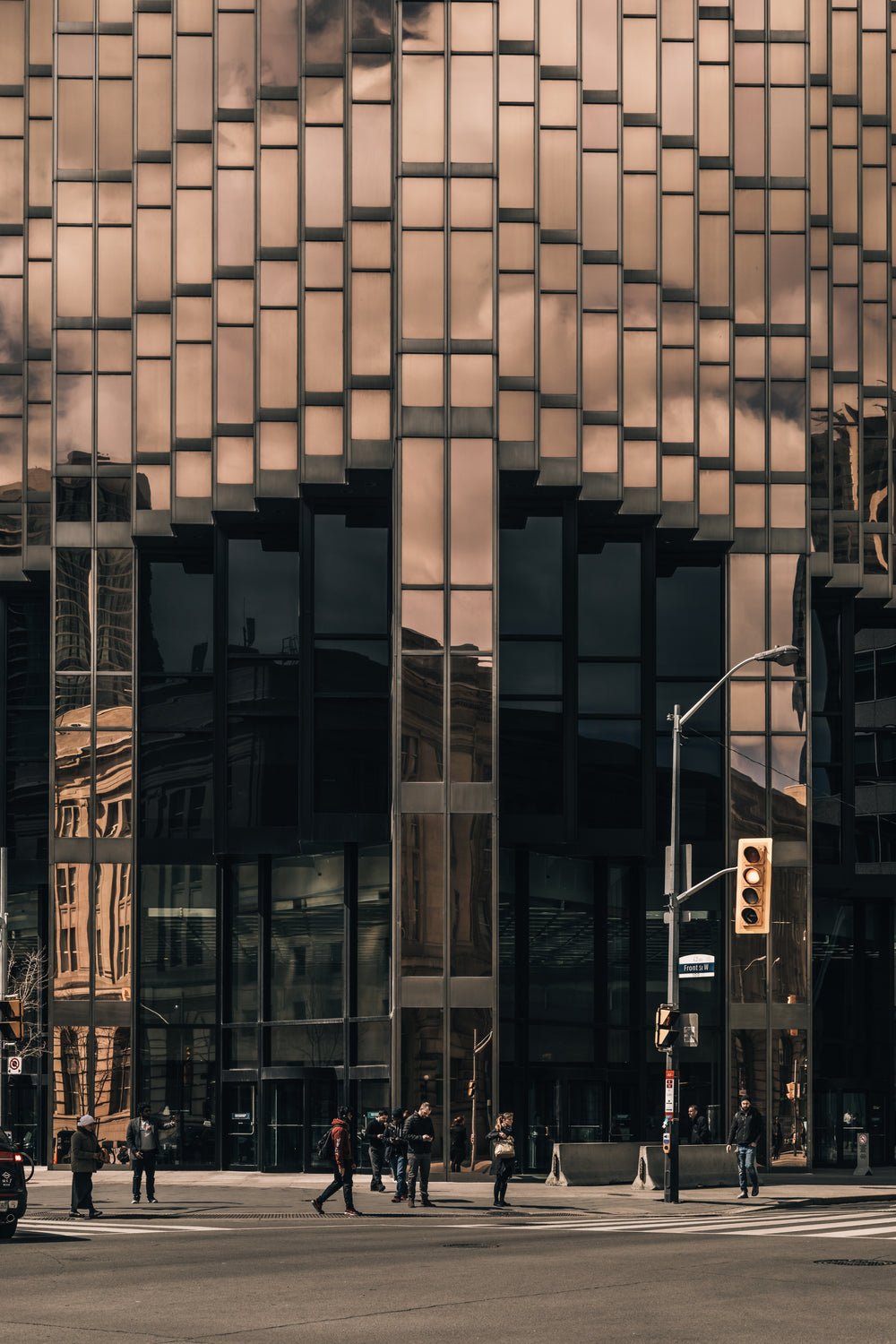 waiting to cross at the feet of metal and glass giants