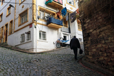 walking up cobblestone street by white and yellow building