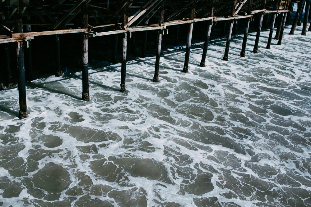 water flowing underneath the shadowy pier