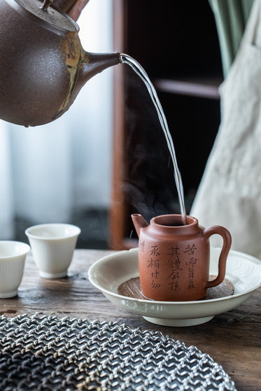 water is poured from one teapot to another