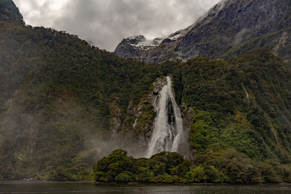 waterfall crashing through rocks below mountains