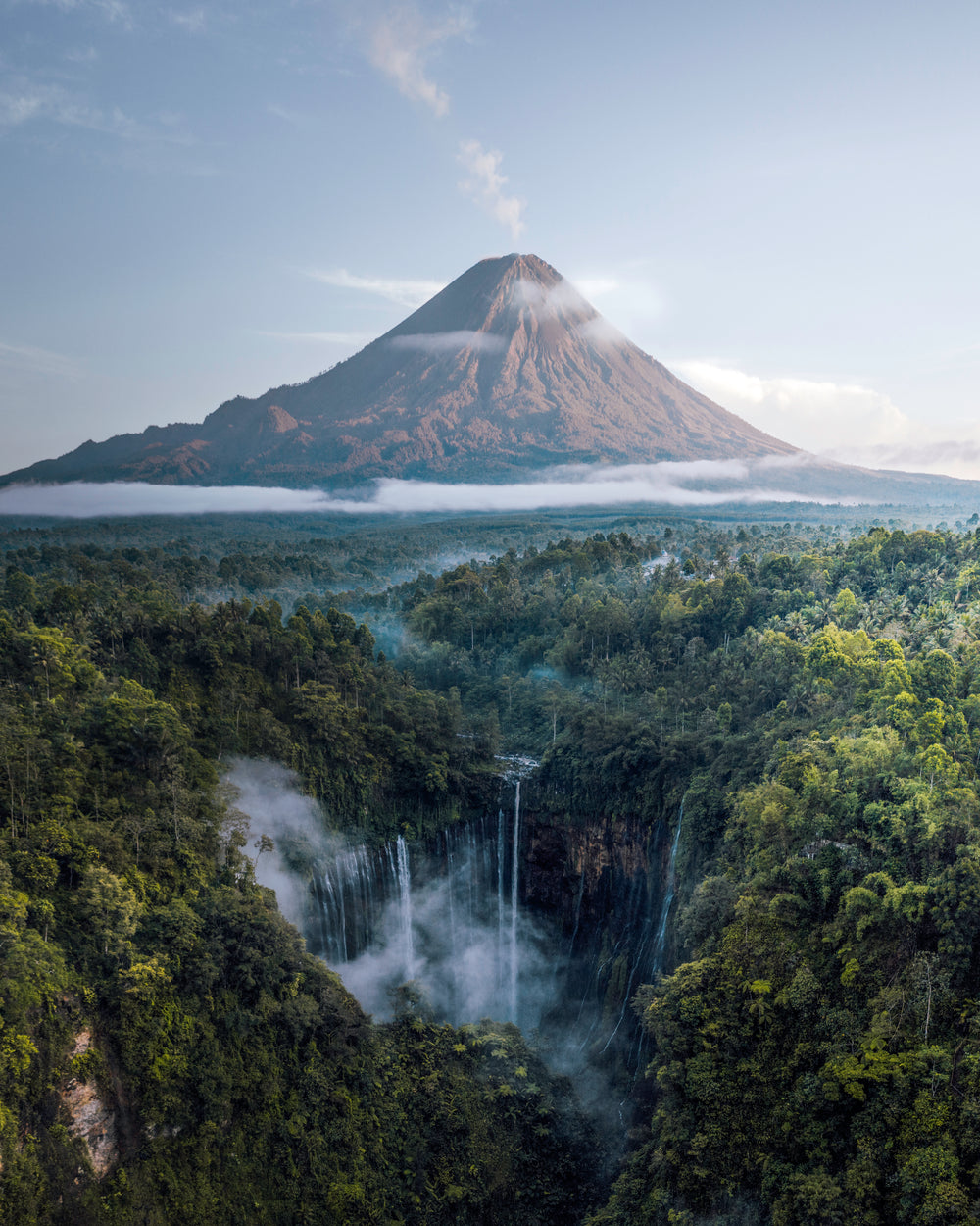 waterfalls in the jungle as a volcano smokes in the distance