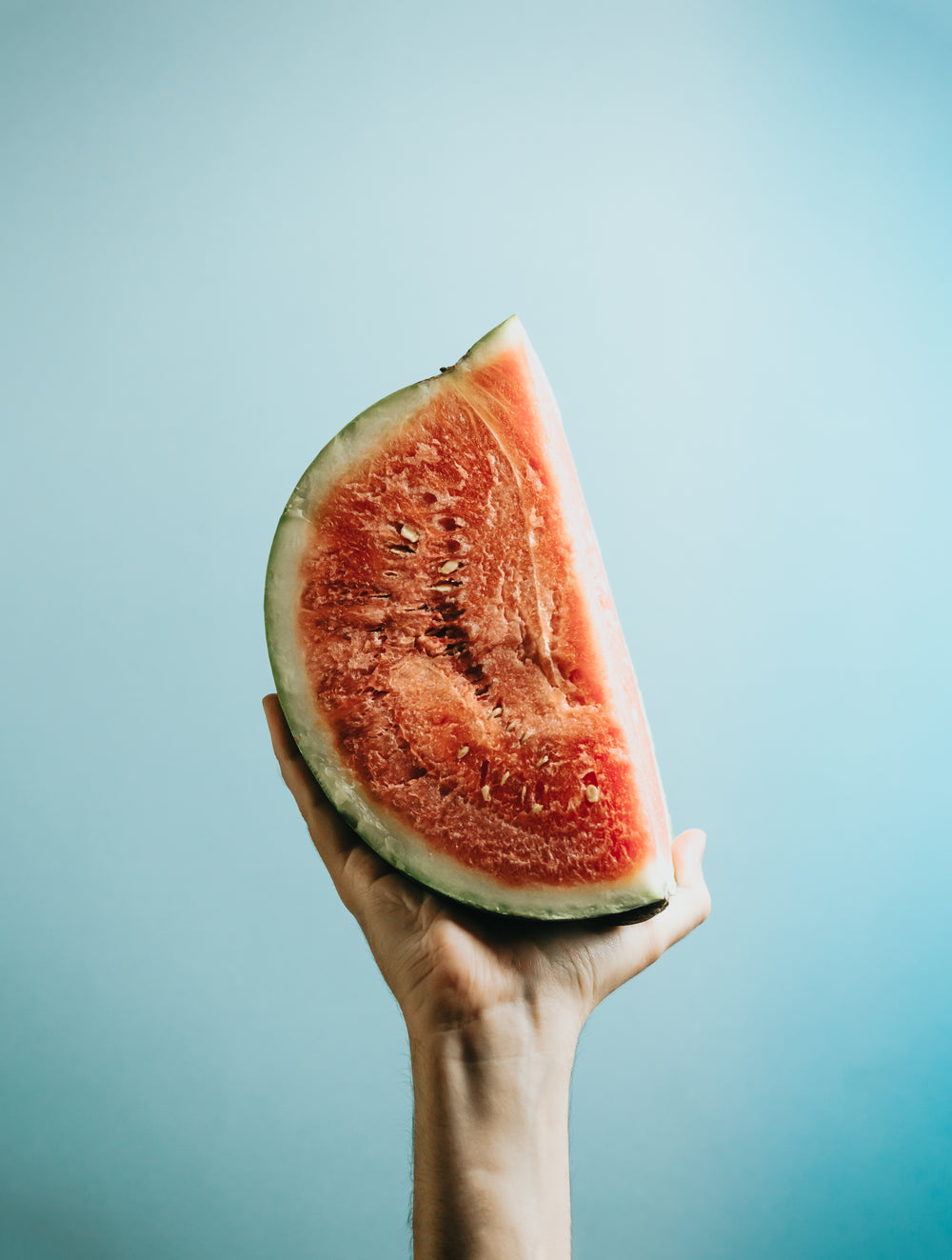 watermelon quarter in the palm against blue background