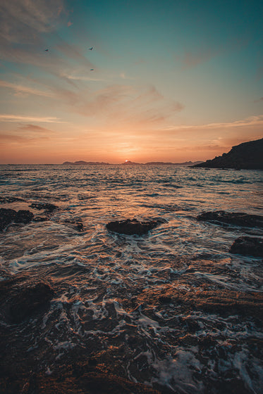 waves rolls over rocks at sunset