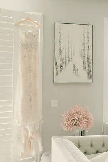 wedding dress hung up by a window