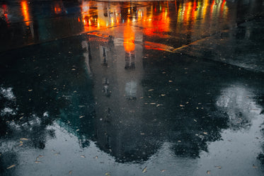 wet pavement reflects a building and city night lights