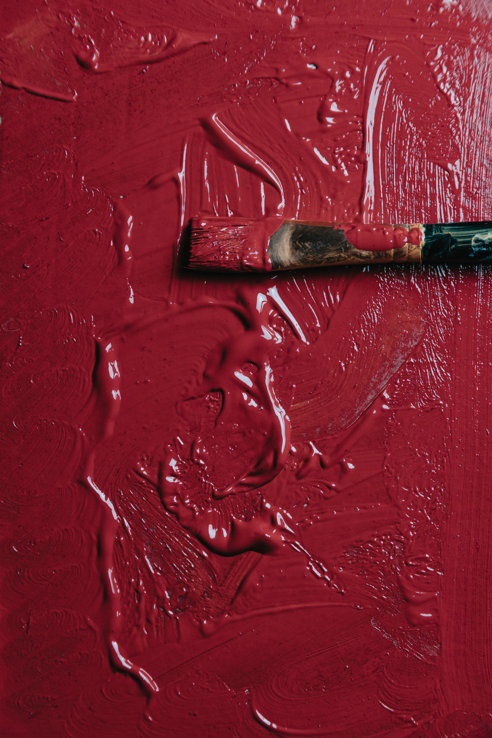 wet red paint with a paint brush laying on it