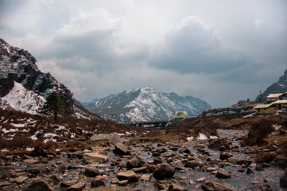 wet rocky land and large snow covered hills