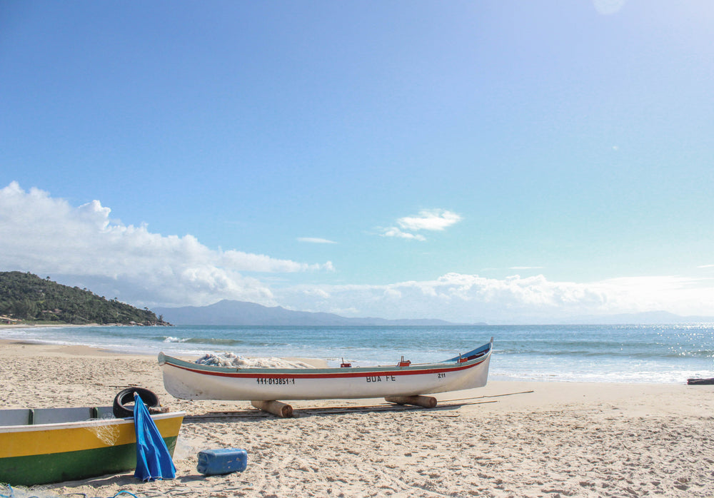 white boat with a red stripe on a sandy beach