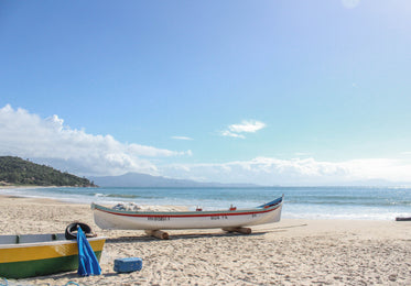 white boat with a red stripe on a sandy beach