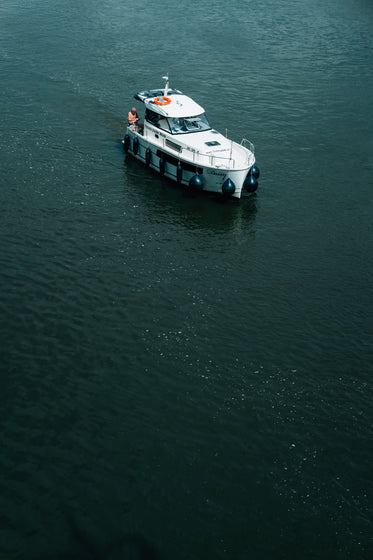 white boat with person in dark blue water