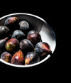 white bowl filled with red figs against black