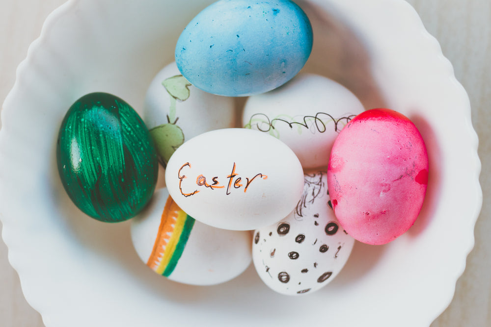 white bowl full of eggs that are decorated for easter