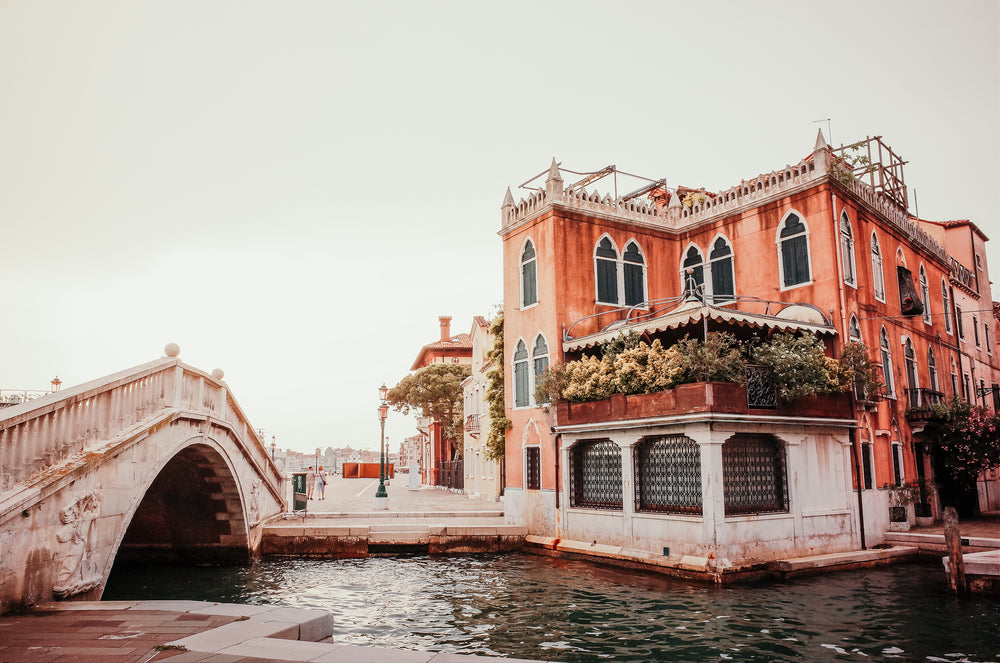 white bridge arches over a canal below an orange building