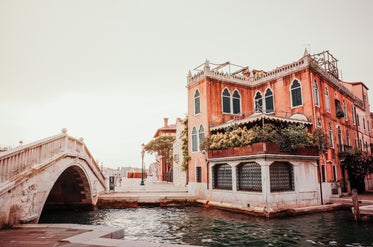 white bridge arches over a canal below an orange building