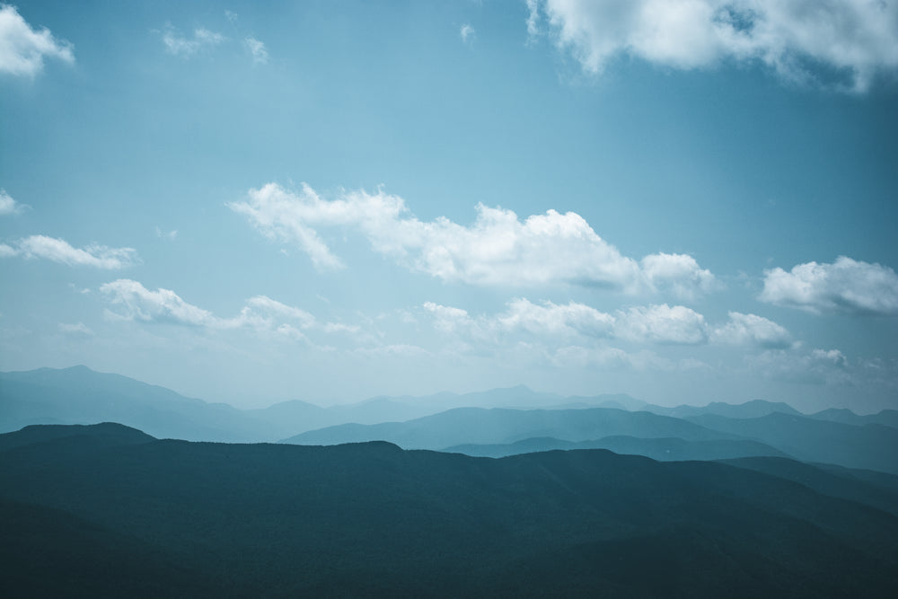 white clouds in a blue sky over hills