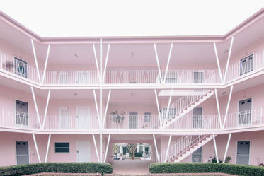 white doors and railings in a pink multi-storey block