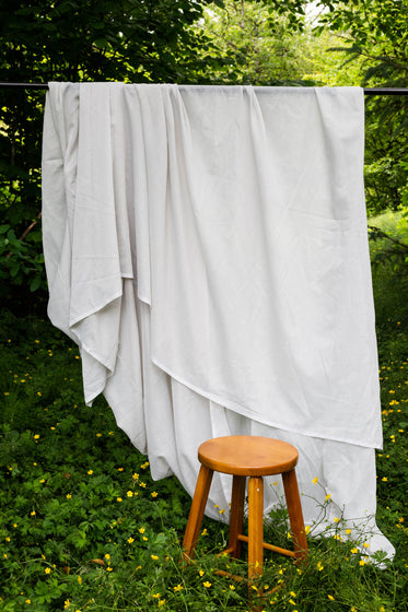 white flowing sheet outdoors with a wooden stool in front of it