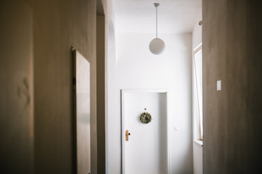 white hallway with a white door and green wreath