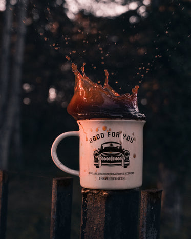 white mug with coffee splashing out of it