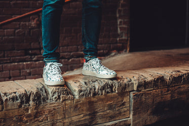 white patterned sneakers on wooden wall
