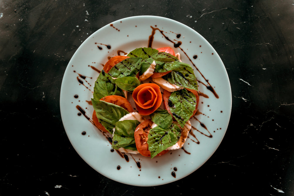 white plate with a caprese salad on it and dressing