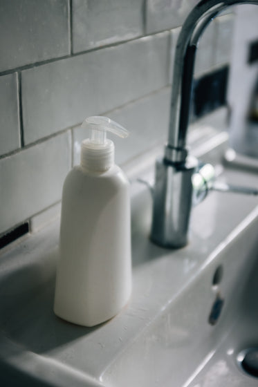 white pump bottle sits on a white porcelain sink