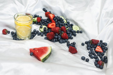 white silk fabric with a glass of lemon water and fresh fruit