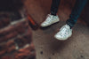white speckled sneakers and dark denim beside brick wall