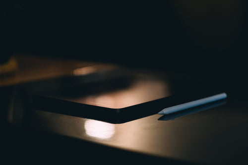 white stylus and a tablet lay on a dark table